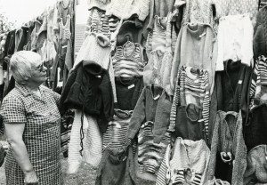 Photo of Mrs Hall with garments made by the Golden Needle League, 1979