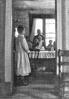 This photograph was taken by a visitor to the Home as the girls were preparing to clear the table after their evening meal. They had just finished their dinner of soup and rice pudding, and the visitor was 'delighted with the behaviour and good appetite of the young folks.' An account of the visit, along with this photograph, appeared in the July 1896 edition of the Society's magazine 'Our Waifs and Strays'.