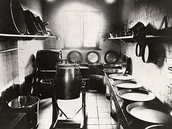 Before the advent of modern technology, all laundry and washing was done manually. This photograph shows all the implements which were required, including metal washing pans, buckets, and barrel clothes spinners.