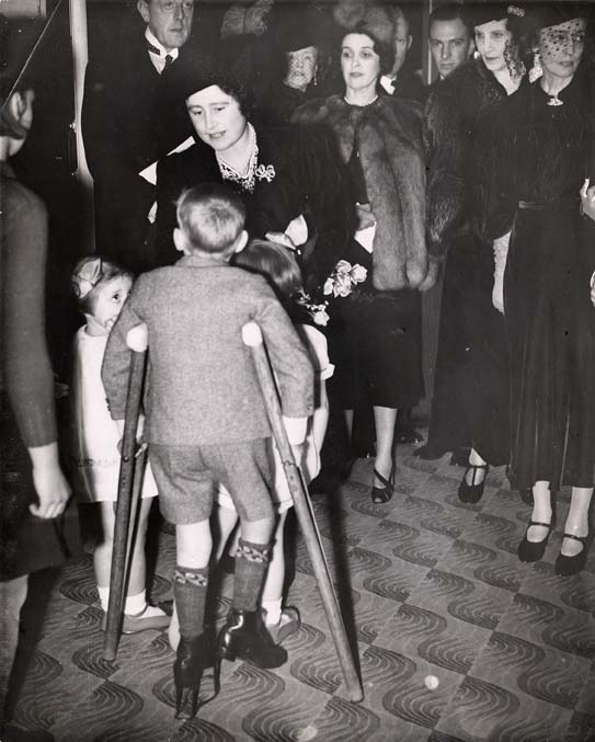 This photograph shows Queen Elizabeth (wife of King George VI and later The Queen Mother) at the Society's annual London Bazaar of 1937. At the event she met several residents from the Pyrford Home for children with disabilities. The Queen took an interest in this area of the Society's work, and had earlier visited Pyrford in 1928 to meet the children.