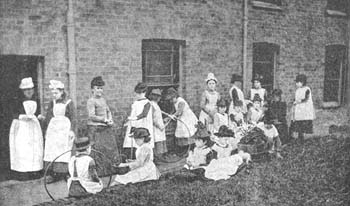 An array of hobbies in the Olive House garden, with some girls looking after their dolls and others preoccupied with their toy hoops. 'Sticks and hoops' was played by rolling the hoops along the ground and tapping them with a short stick, to keep them moving as long as possible.